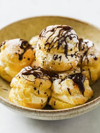 a bowl of Profiteroles drizzled in chocolate