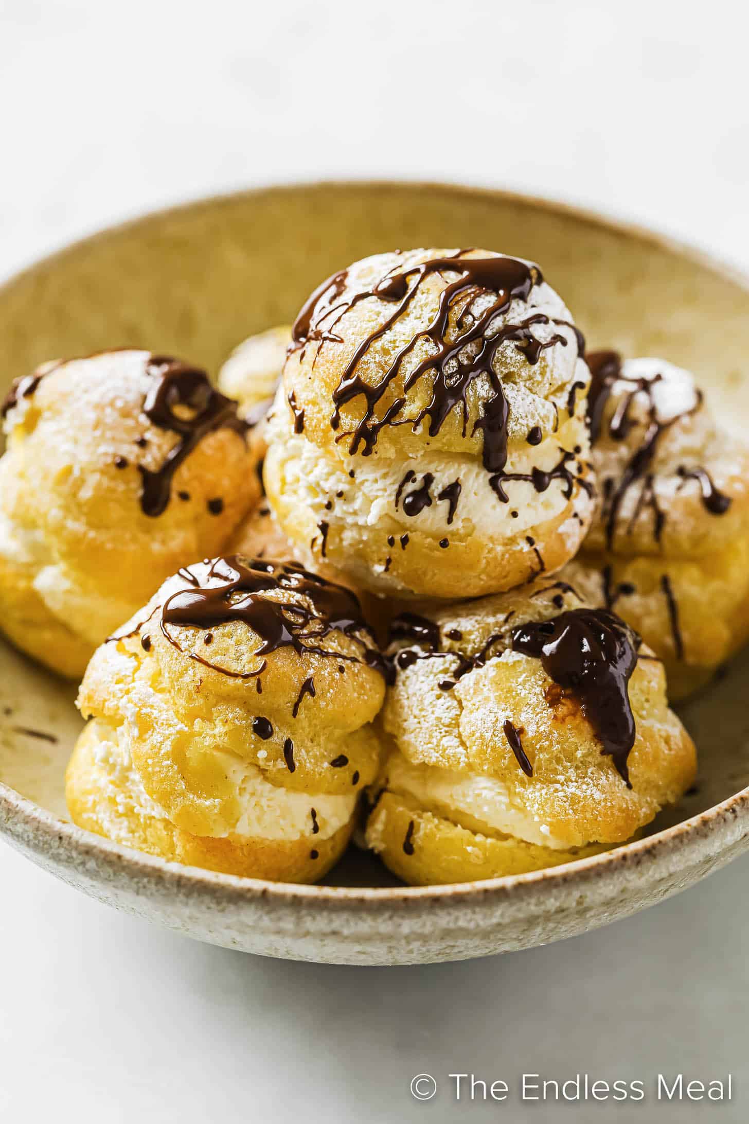 a bowl of Profiteroles  drizzled in chocolate