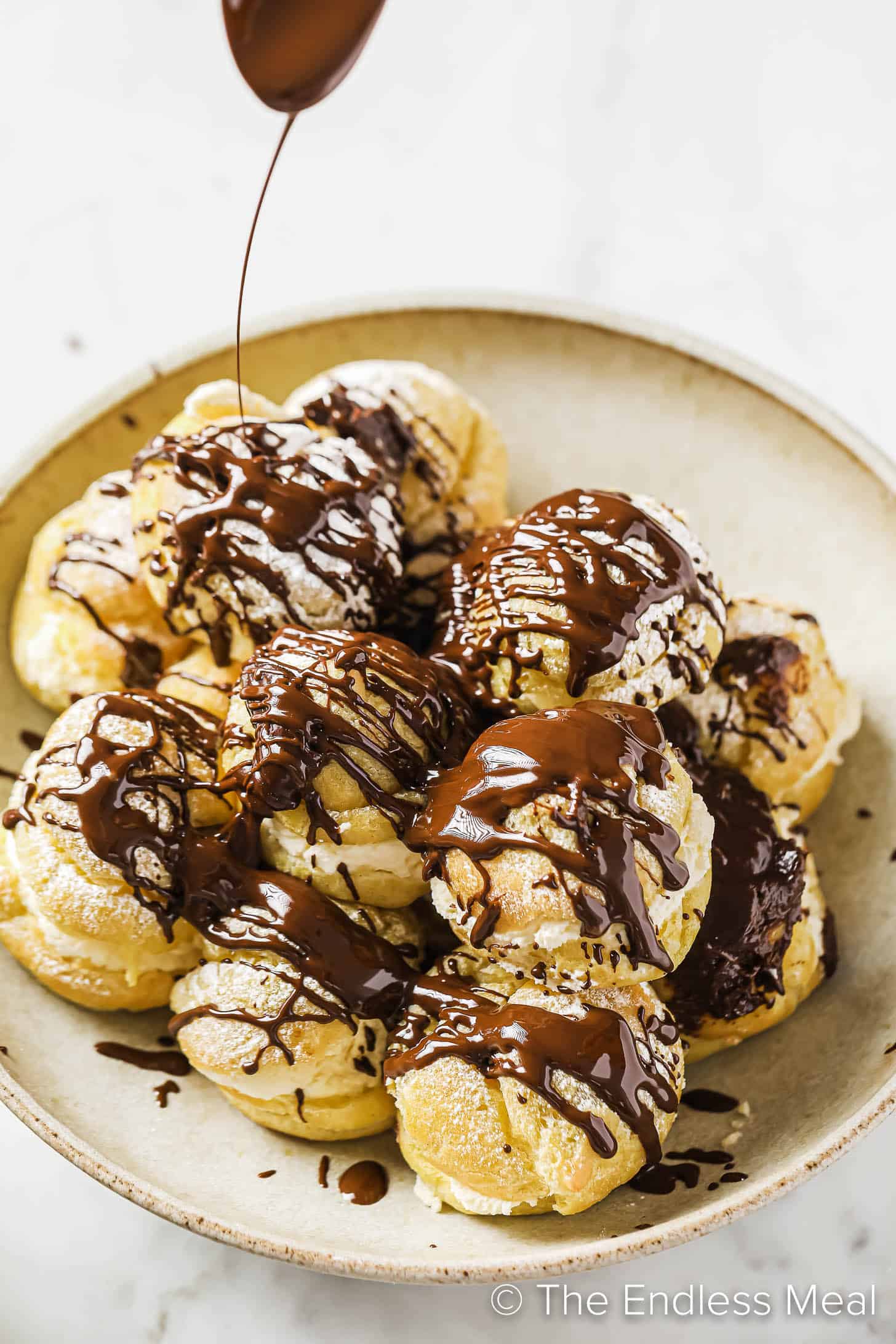 chocolate sauce being poured over Profiteroles