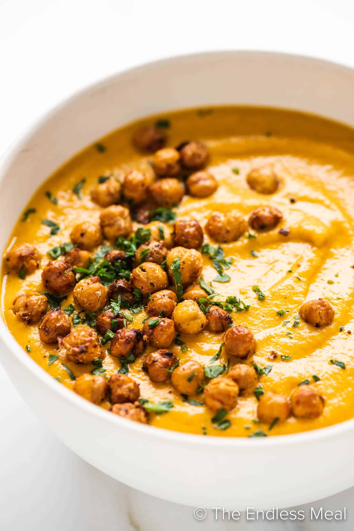 crispy chickpea croutons on top of Roasted Carrot Soup in a bowl