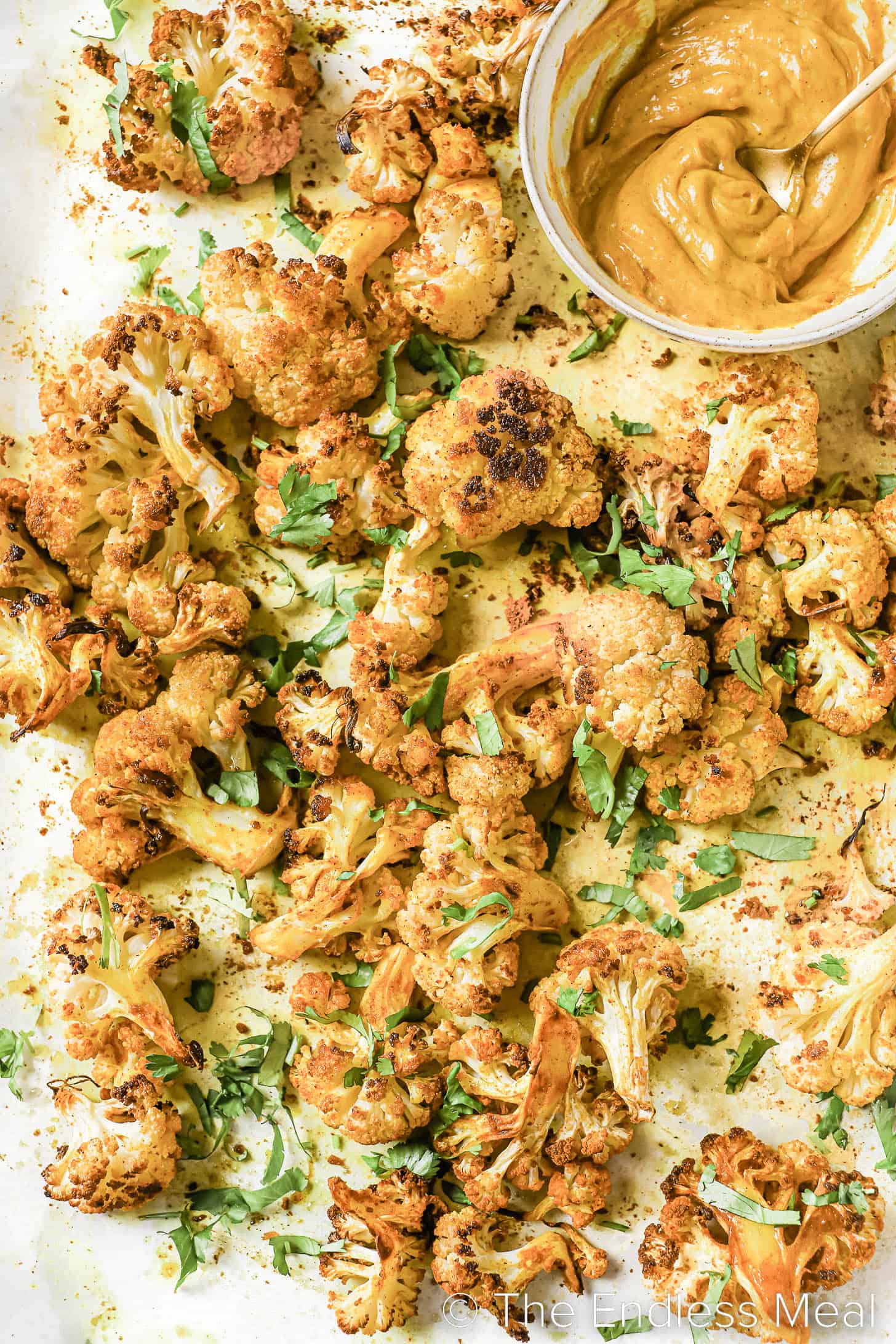 a baking pan with Curried Cauliflower Bites and curry mayo on the side