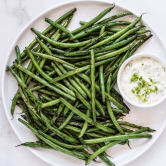 a plate of green beans with garlic scapes aioli