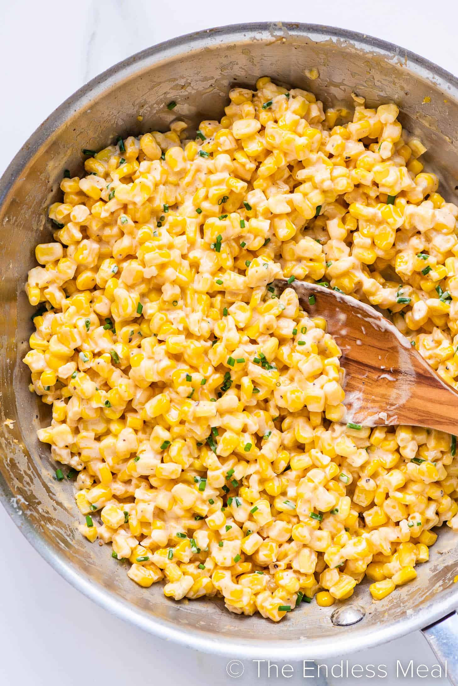 Honey Butter Skillet Corn in a pan with a wooden spoon