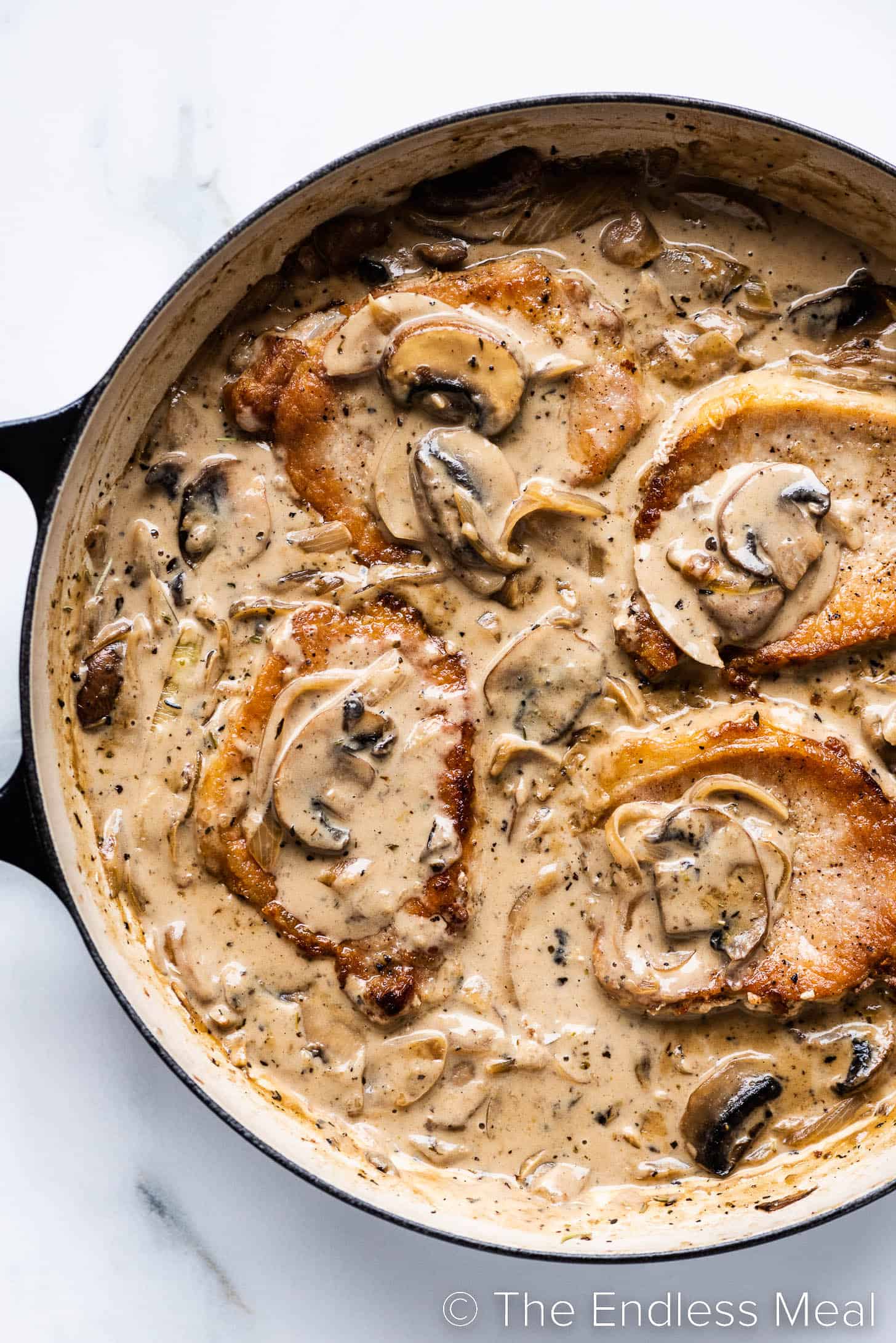 a pan of pork chops smothered in a mushroom onion gravy