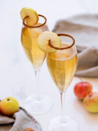 Champagne flutes with Apple Cider Mimosa and an apple ring garnish.