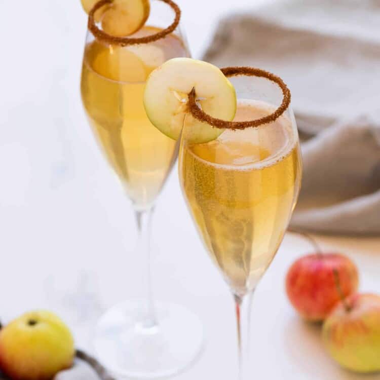 Champagne flutes with Apple Cider Mimosa and an apple ring garnish.