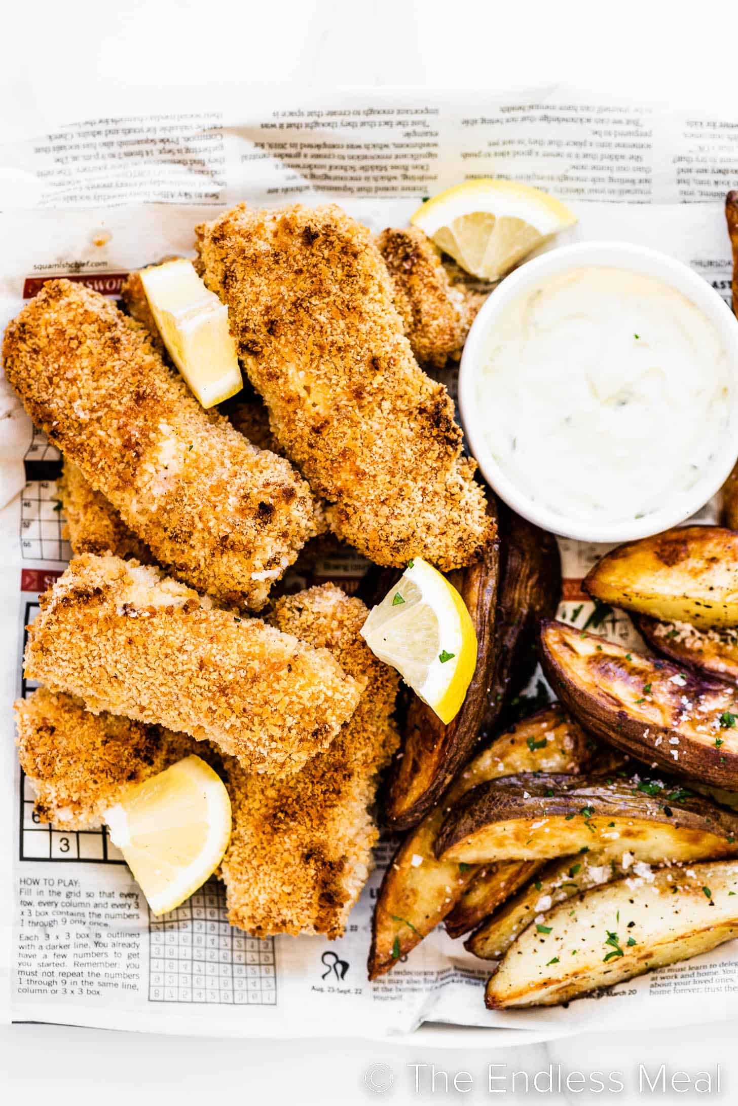 a platter of baked fish and chips with tartar sauce