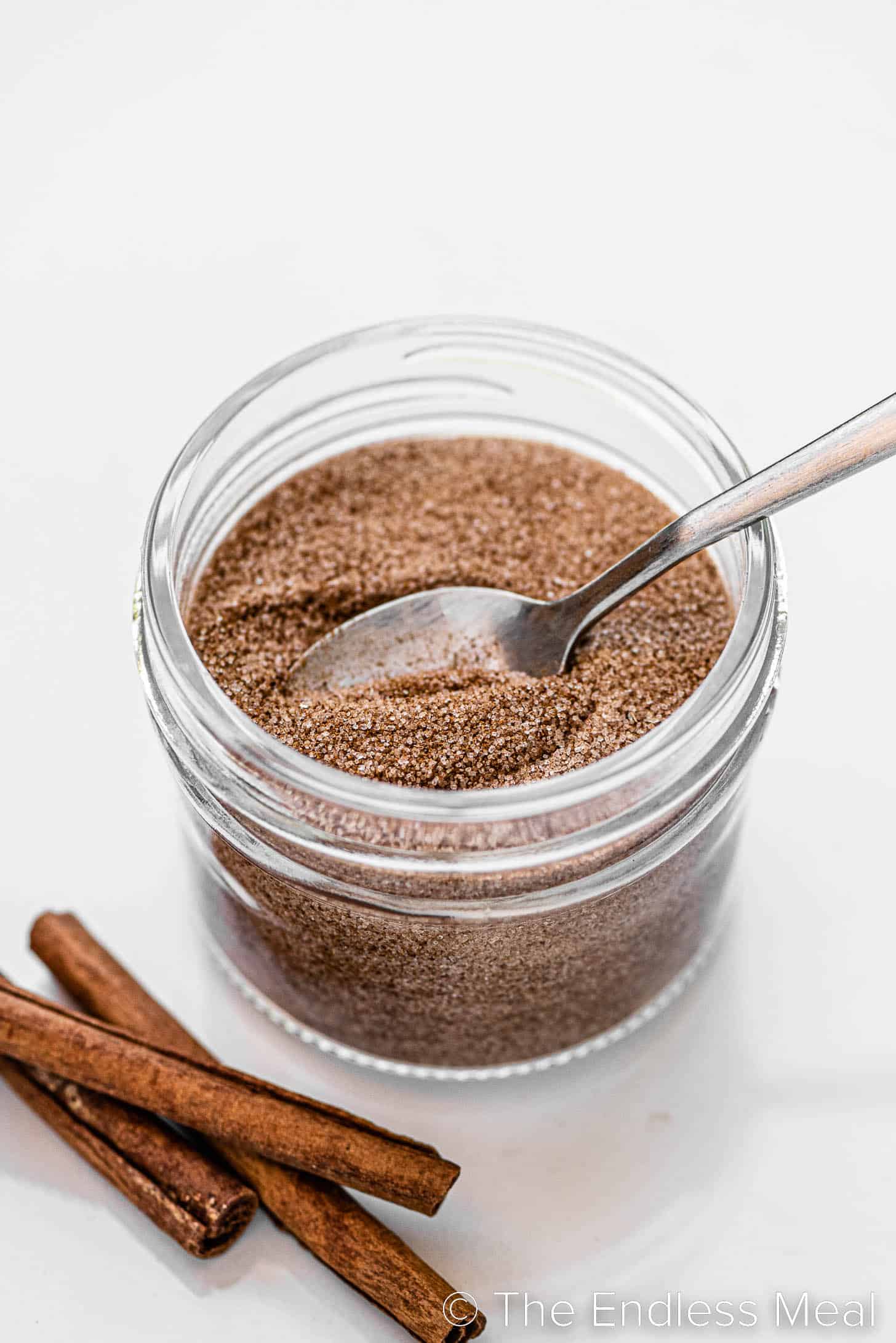 a spoon scooping some cinnamon sugar out of a jar.