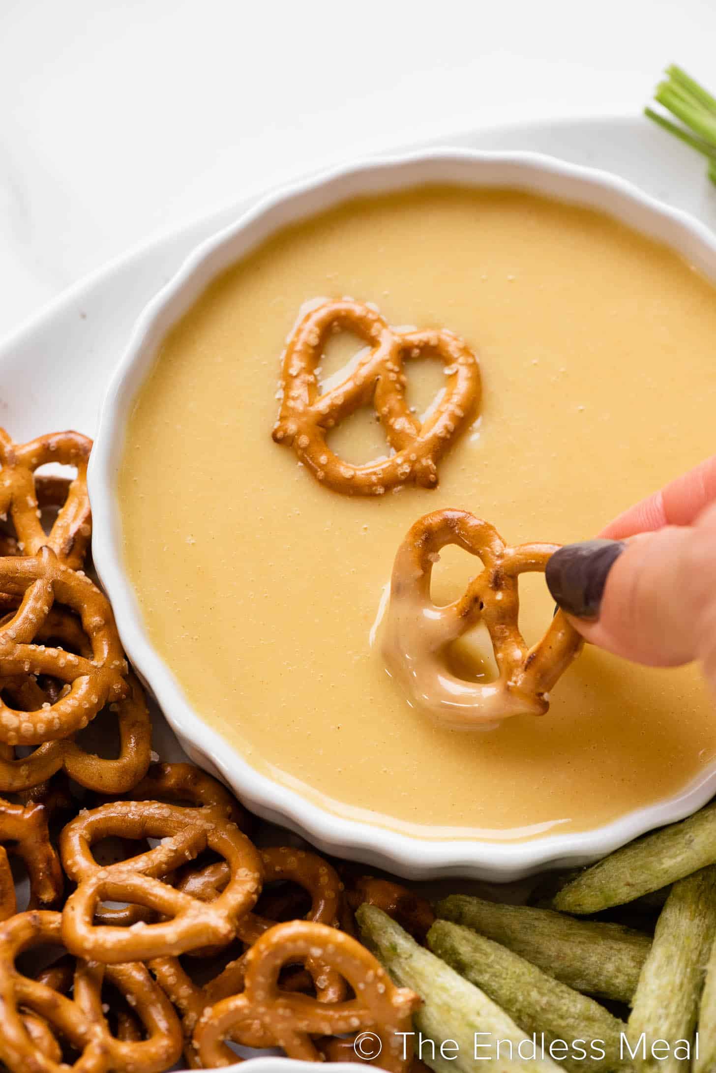 a hand dipping a pretzel in one of the easy party dips