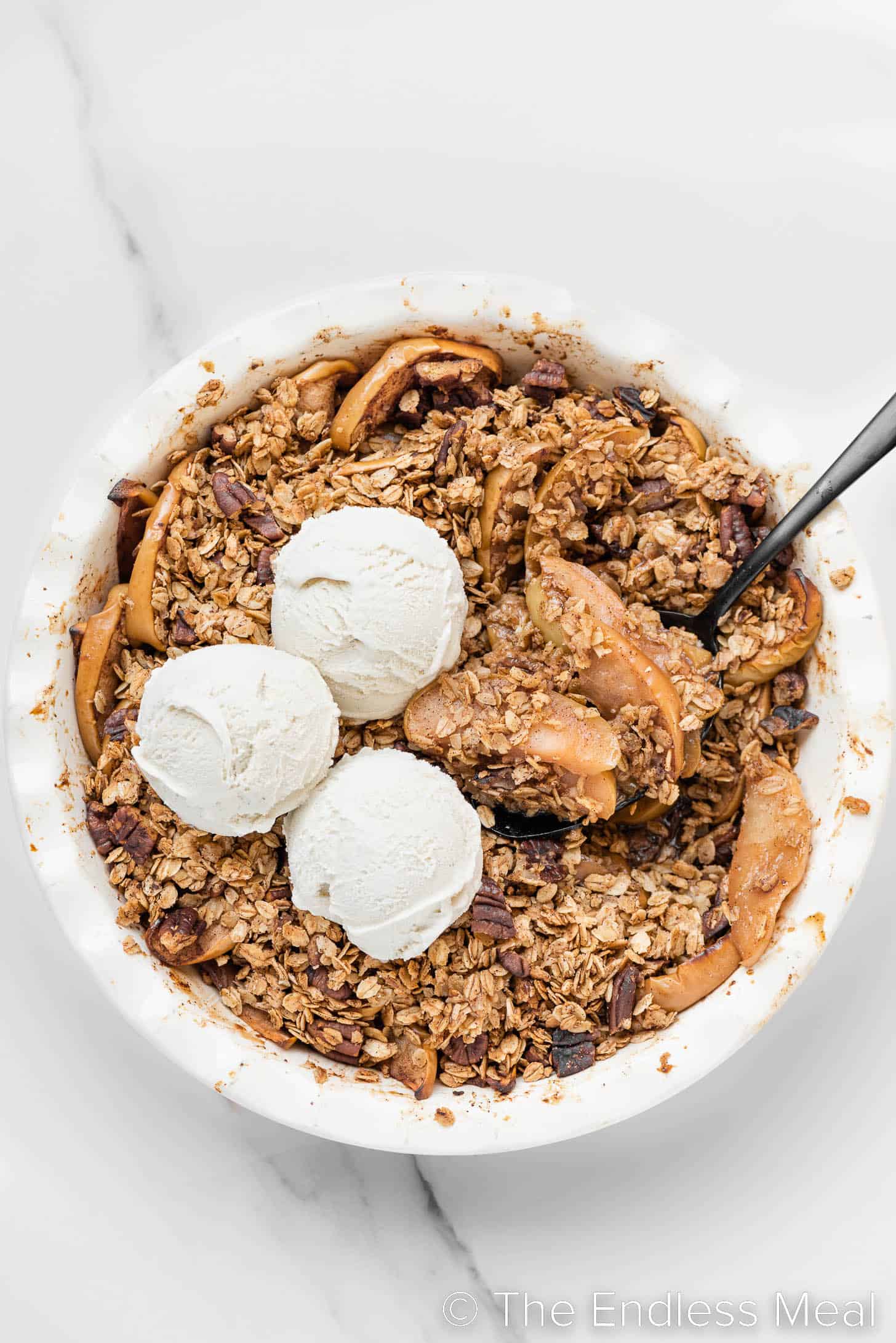 a pie pan with Healthy Apple Crisp and some ice cream on top.