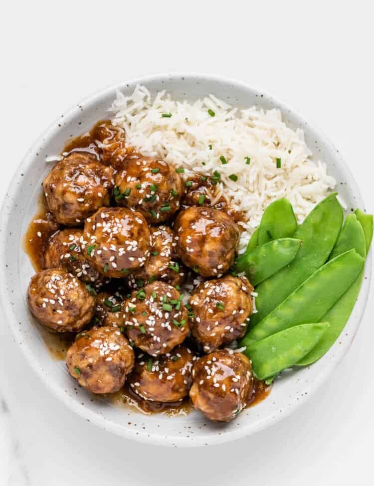 Honey Garlic Meatballs on a plate with rice and snow peas.