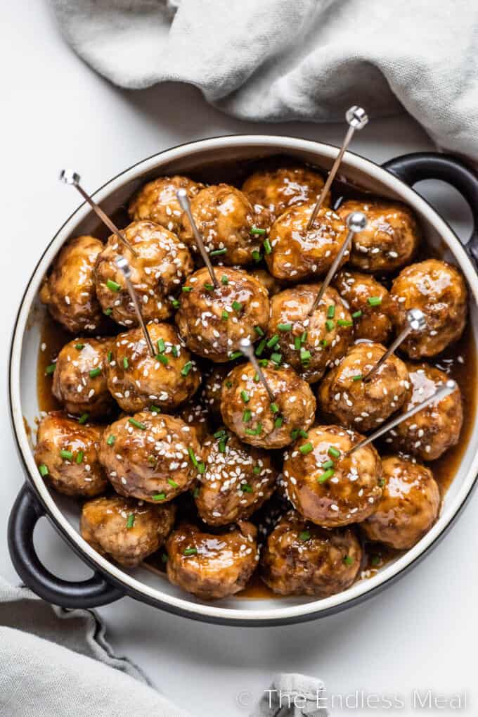 Honey Garlic Meatballs in a serving bowl with appetizer skewers