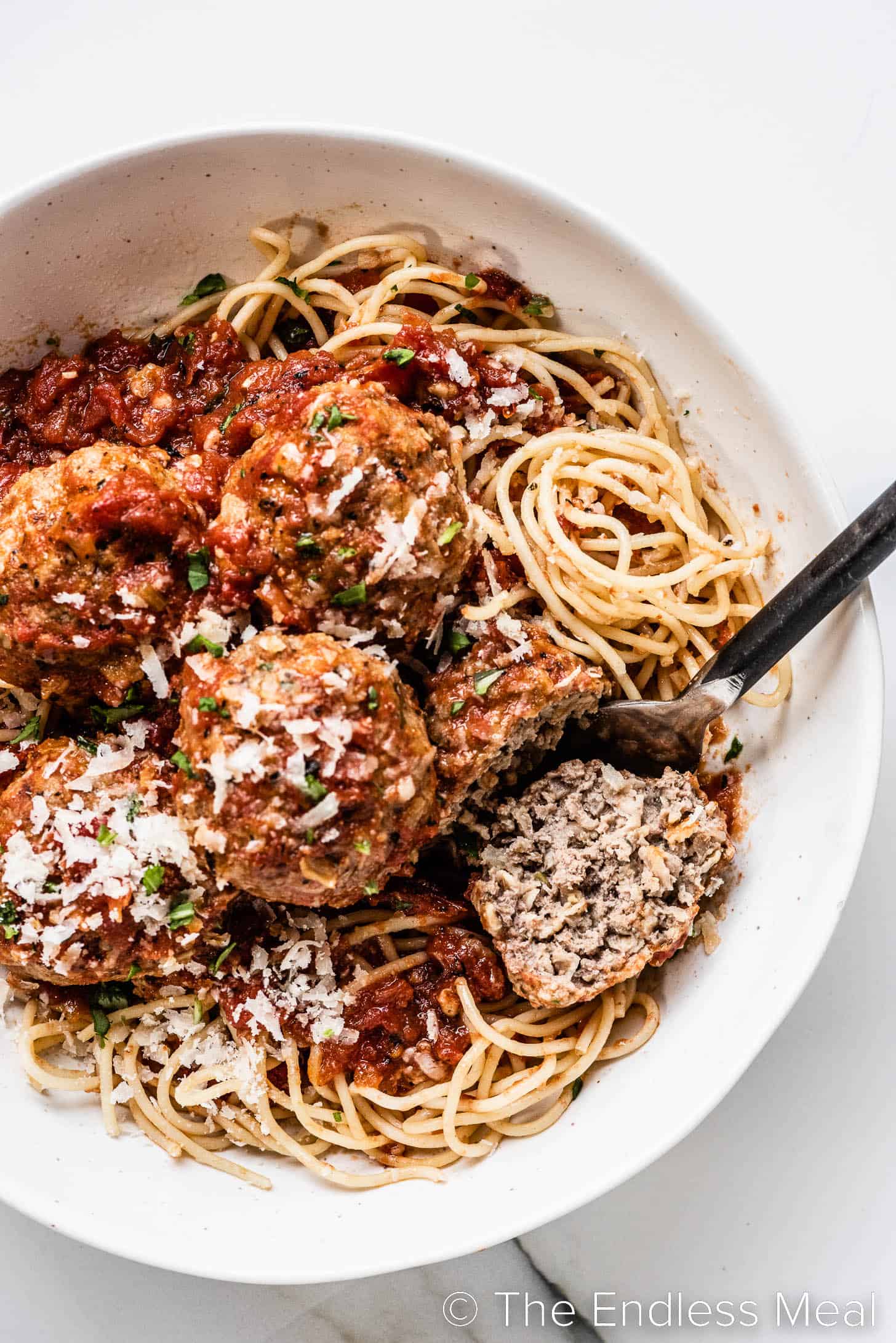 a close up of a meatball cut in half on top of spaghetti