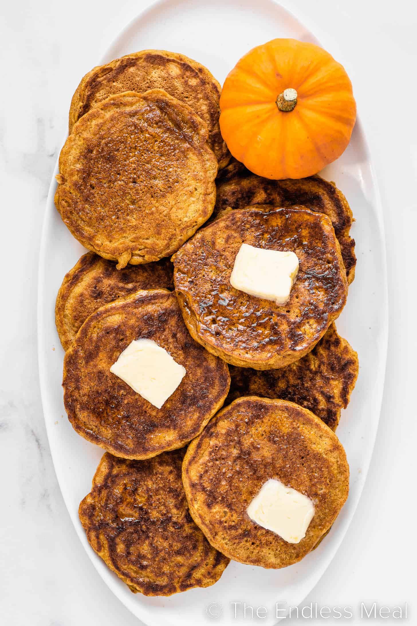 a serving platter stacked with pumpkin spice pancakes