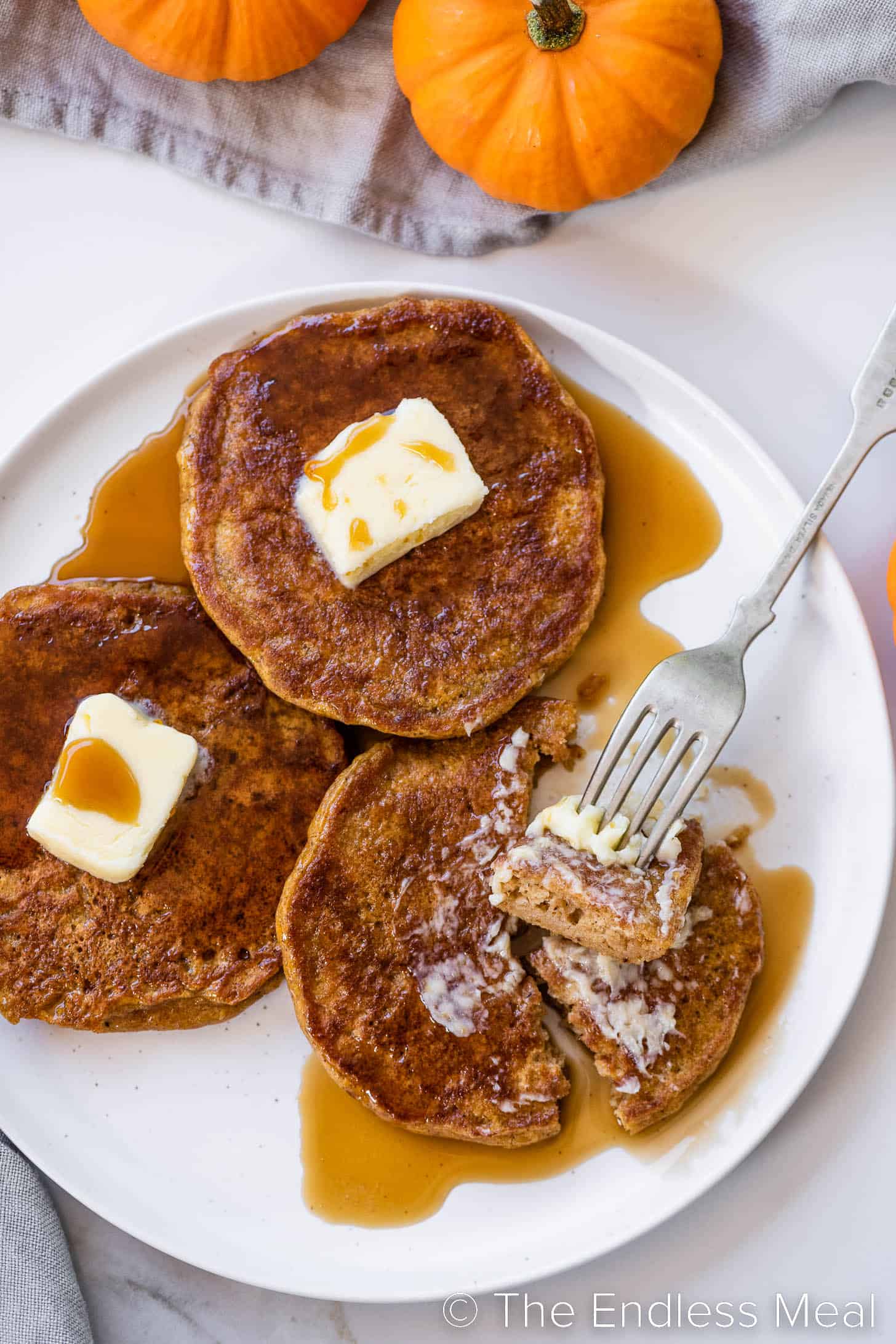 Pumpkin Pancakes on a plate with a fork taking a bite