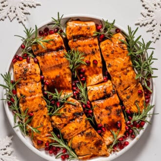 Christmas Salmon on a serving plate with rosemary and pomegranate seeds.
