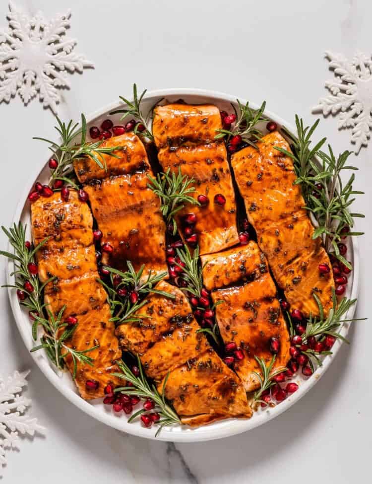 Christmas Salmon on a serving plate with rosemary and pomegranate seeds.