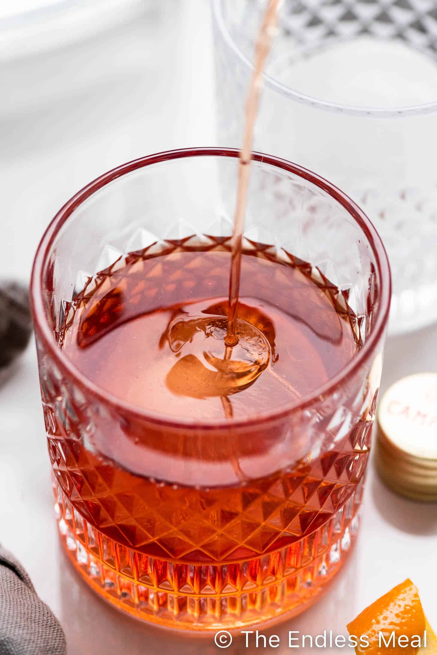 pouring a negroni into a glass with ice