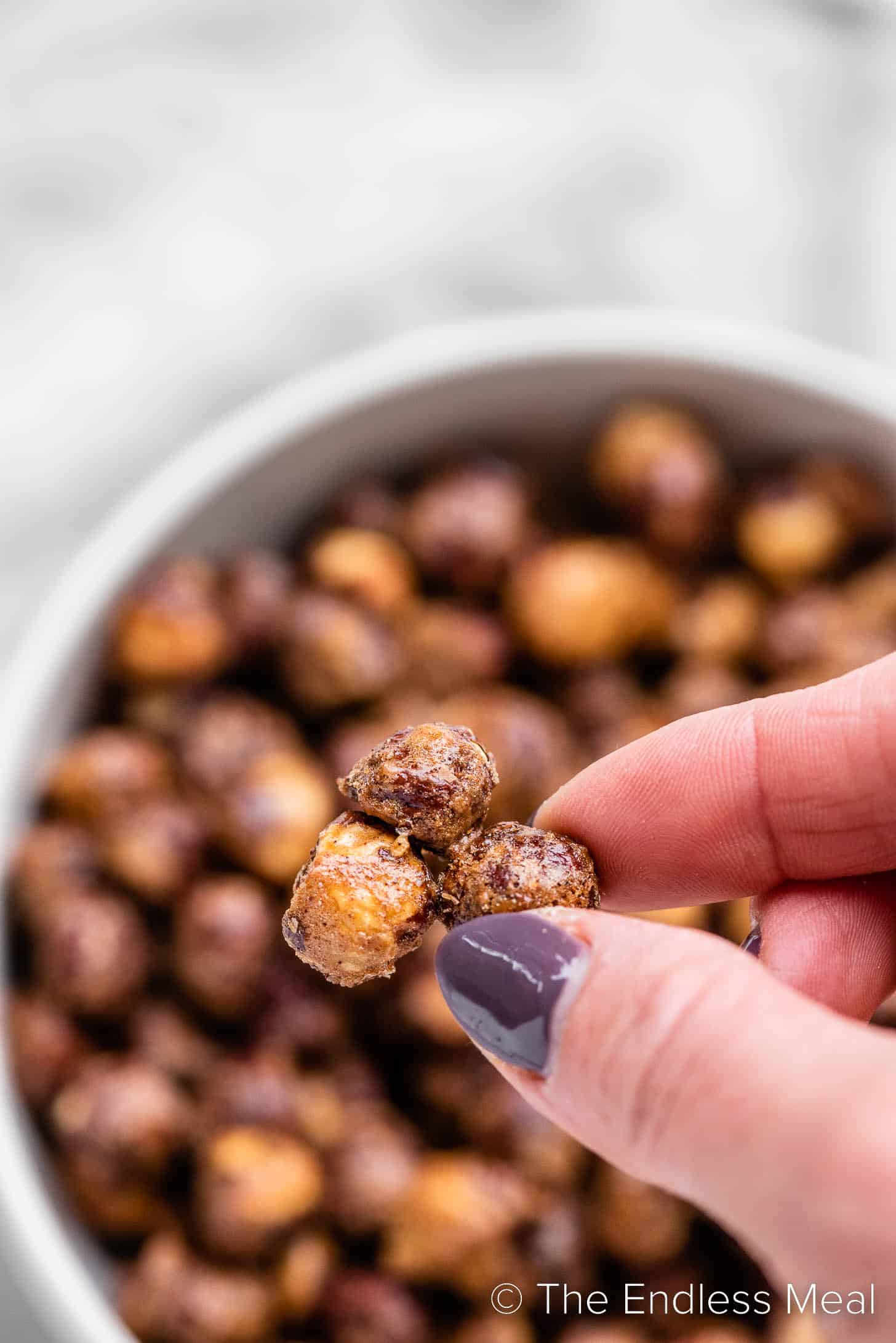 a hand holding a cluster of Candied Hazelnuts
