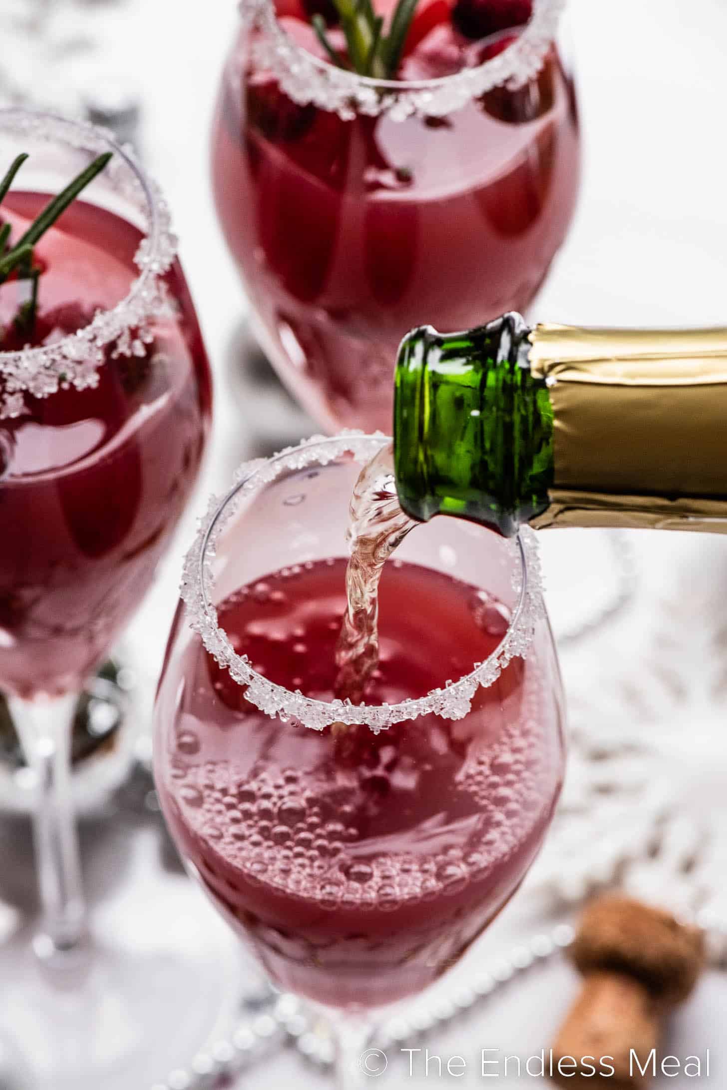 Sparkling wine being poured into a champagne flute with cranberry juice