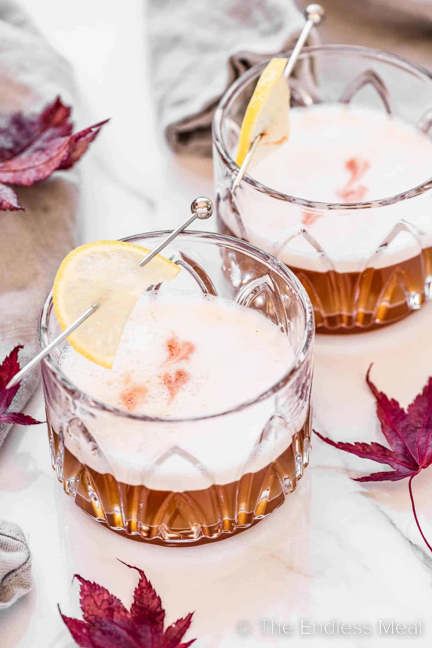 Two Maple Bourbon Sours surrounded by maple leaves