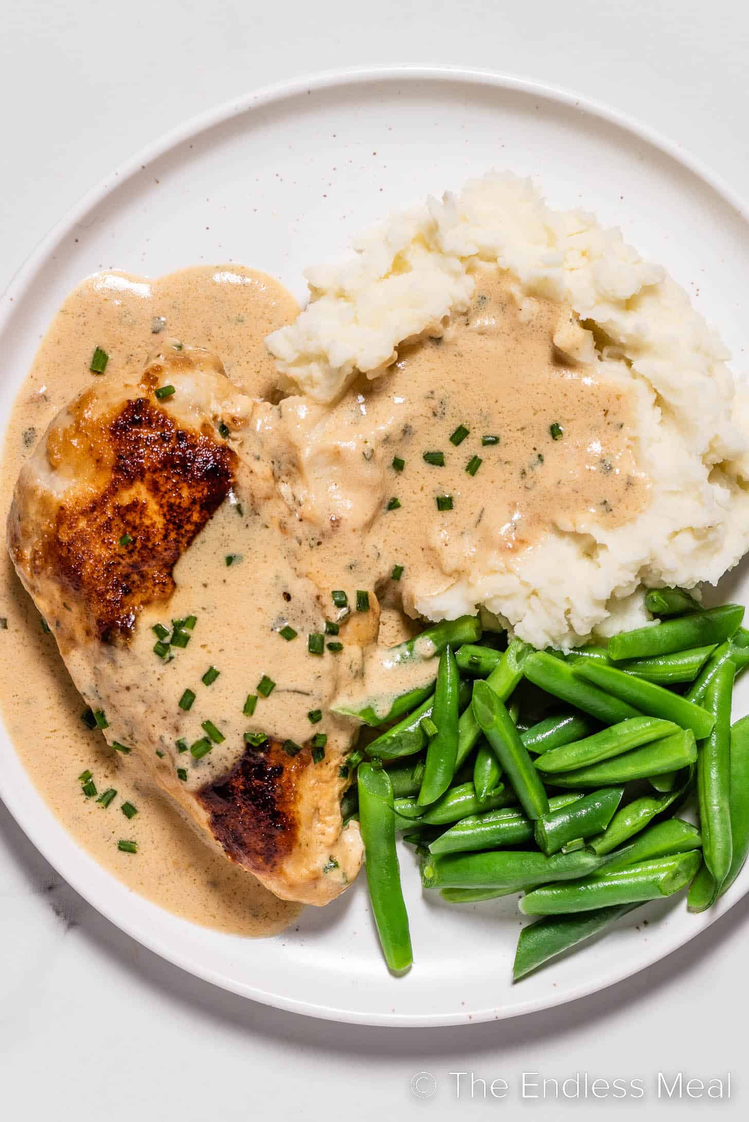 Boursin Chicken on a dinner plate with mashed potatoes and green beans.