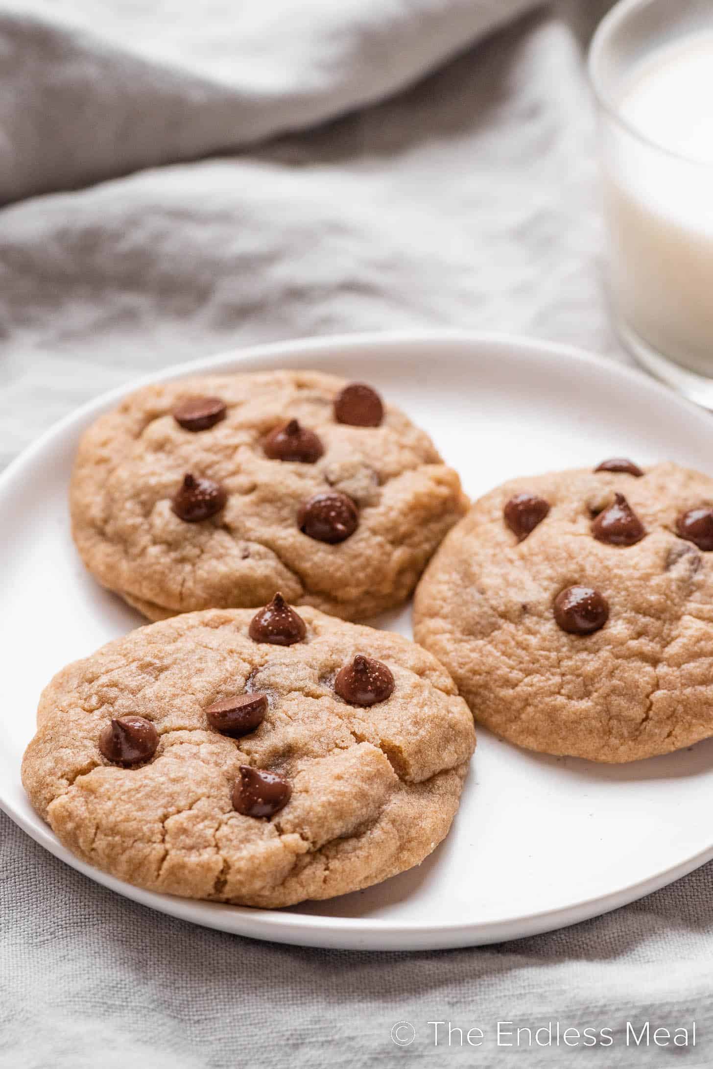 Whole Wheat Chocolate Chip Cookies on a plate next to a glass of milk.