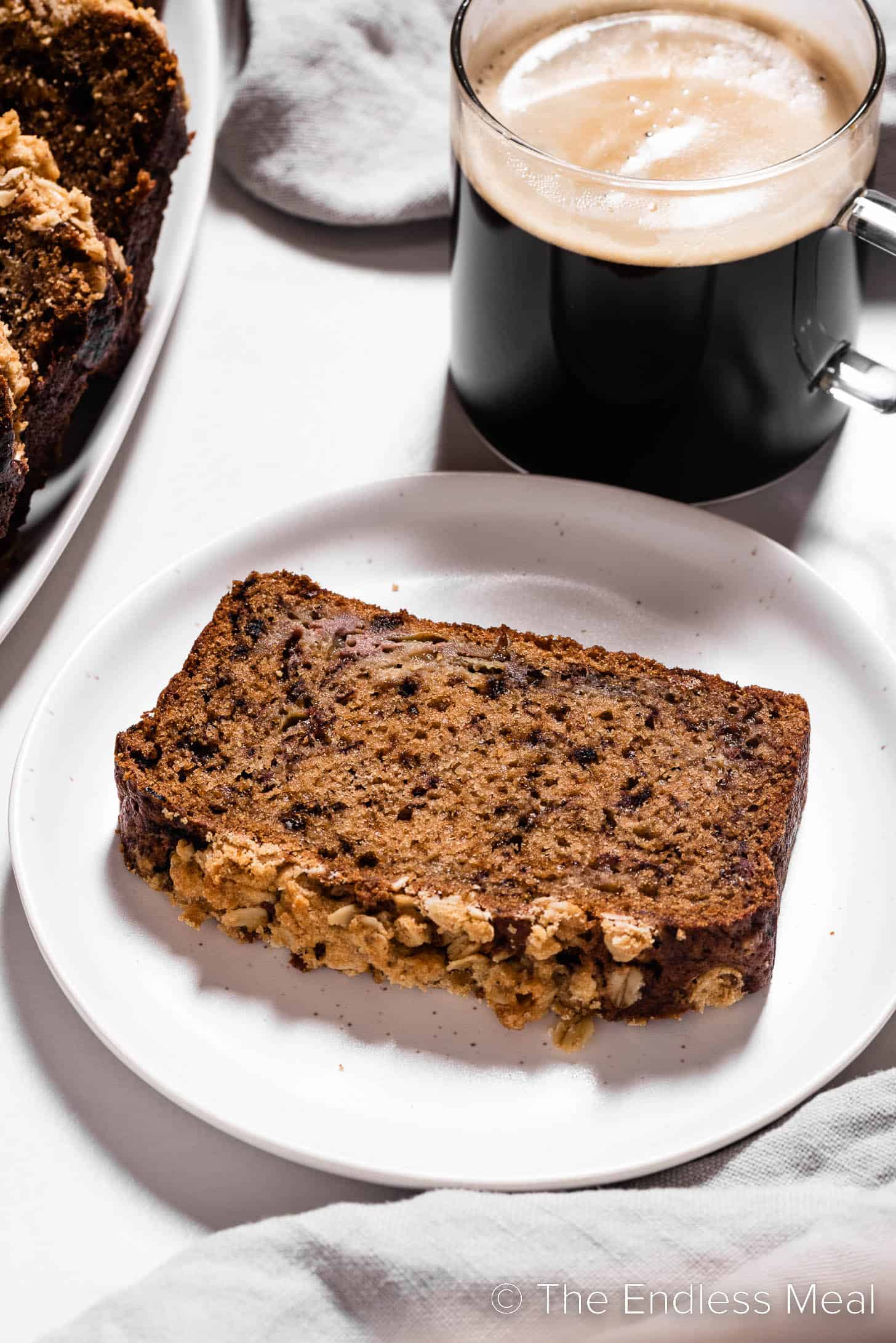 Coffee cake banana bread next to a cup of coffee.