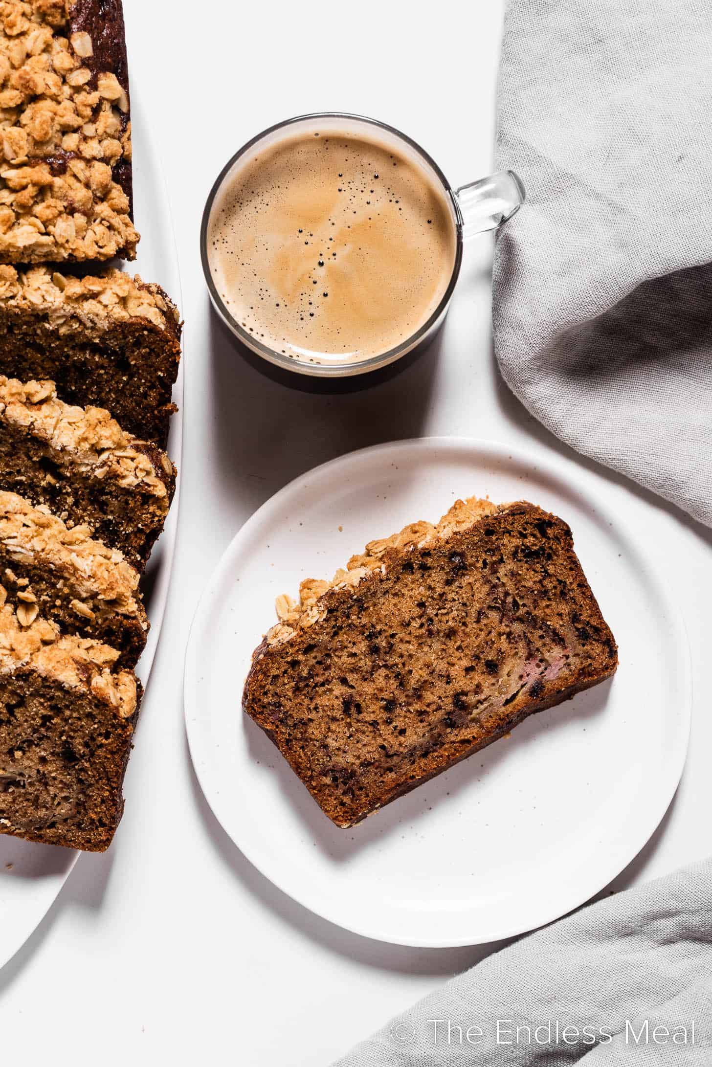 A slice of Coffee Banana Bread next to a cup of coffee