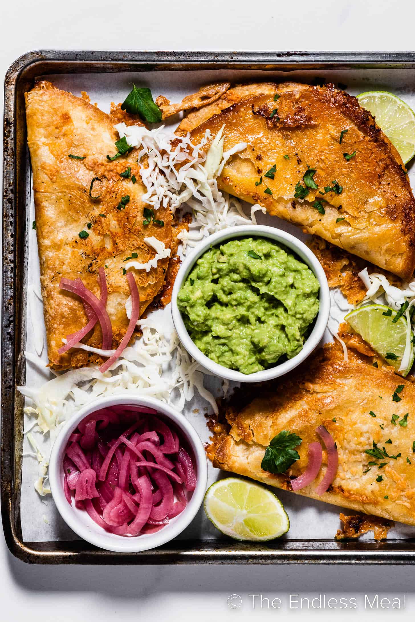 Crispy Sheet Pan Shrimp Tacos with guacamole and pickled red onions.