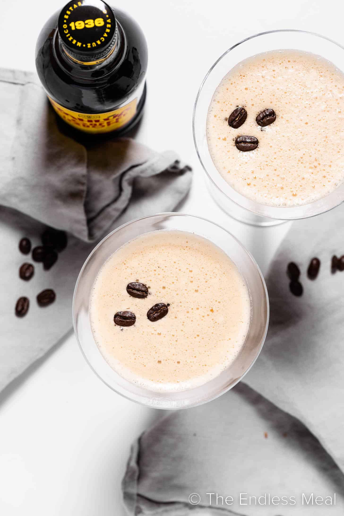 Looking down on an espresso martini with coffee beans and a bottle of Kahlua