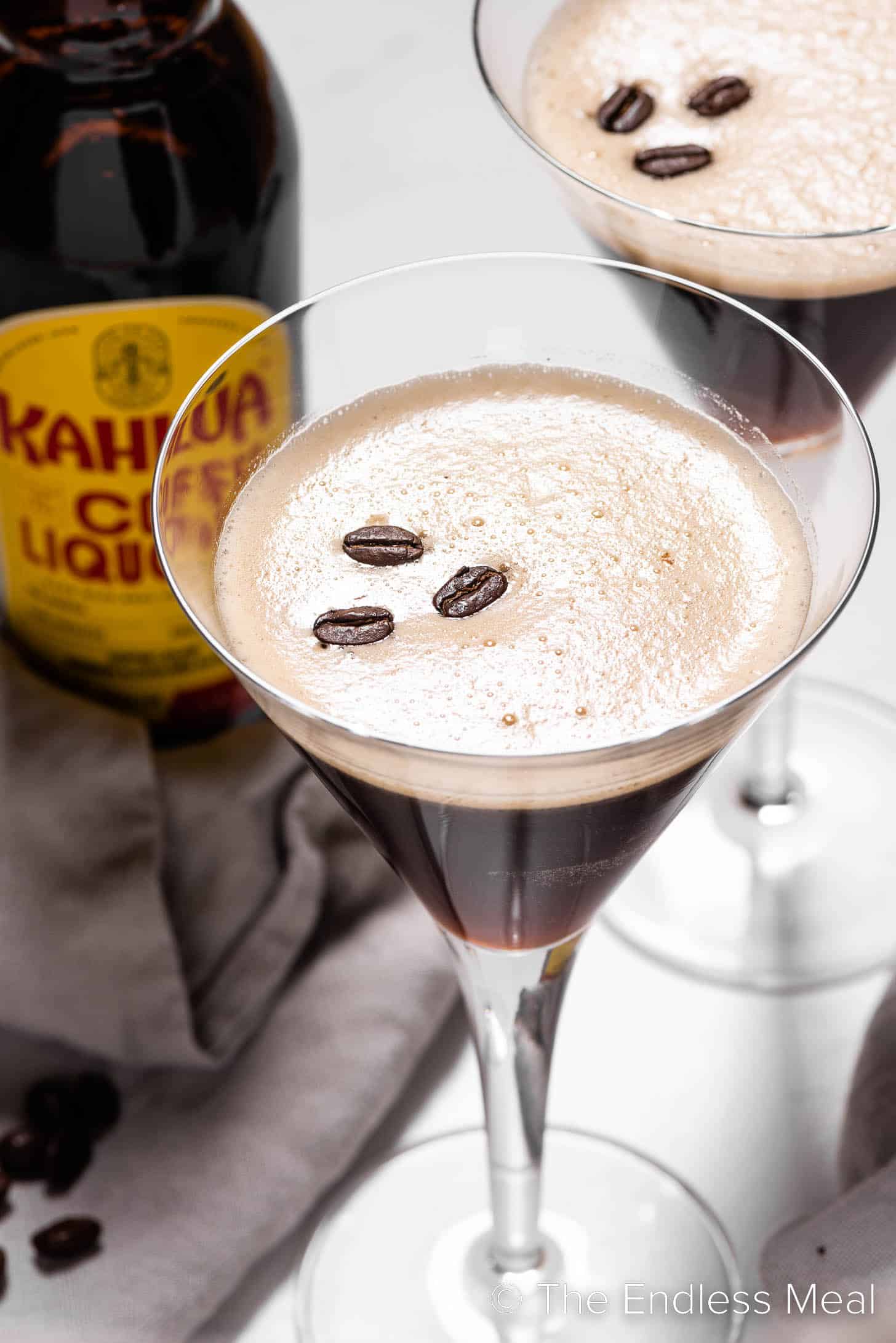 Two espresso martinis with a bottle of Kahlua.