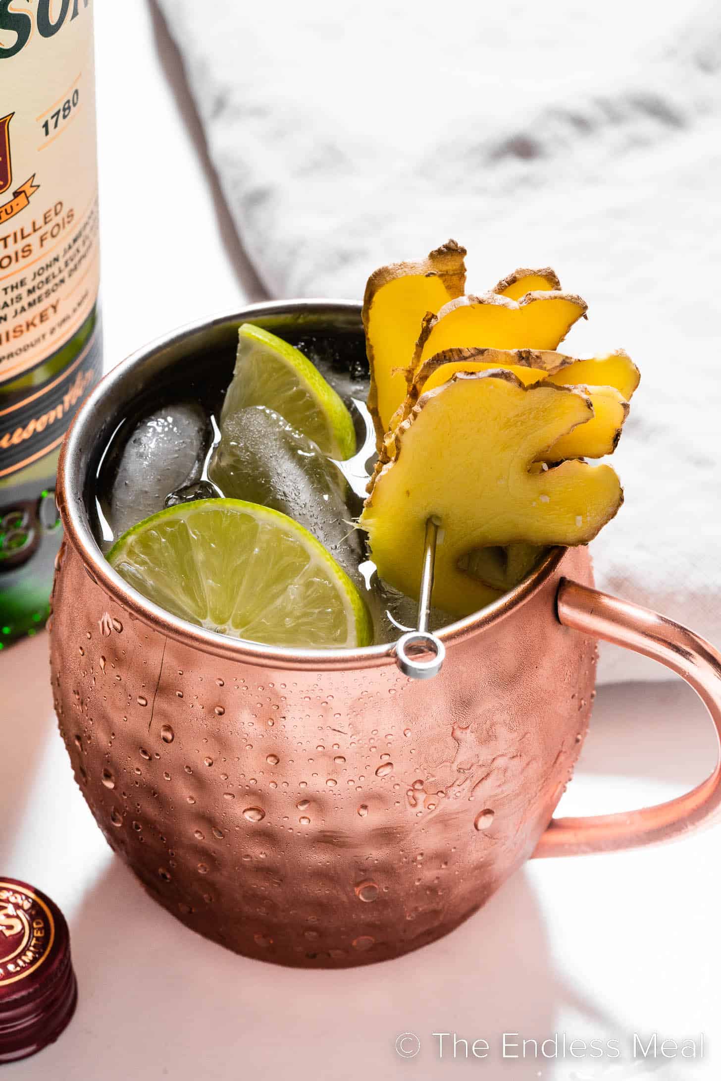An Irish Mule in a copper mug garnished with fresh ginger and limes