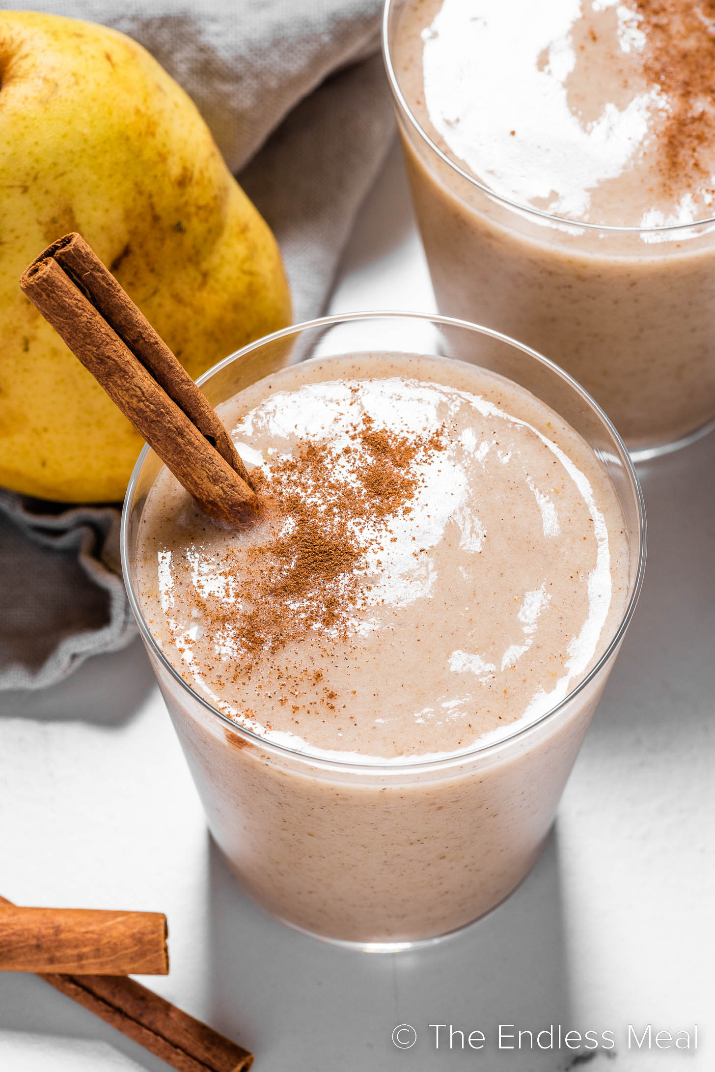 A Pear Smoothie in a glass with a cinnamon stick