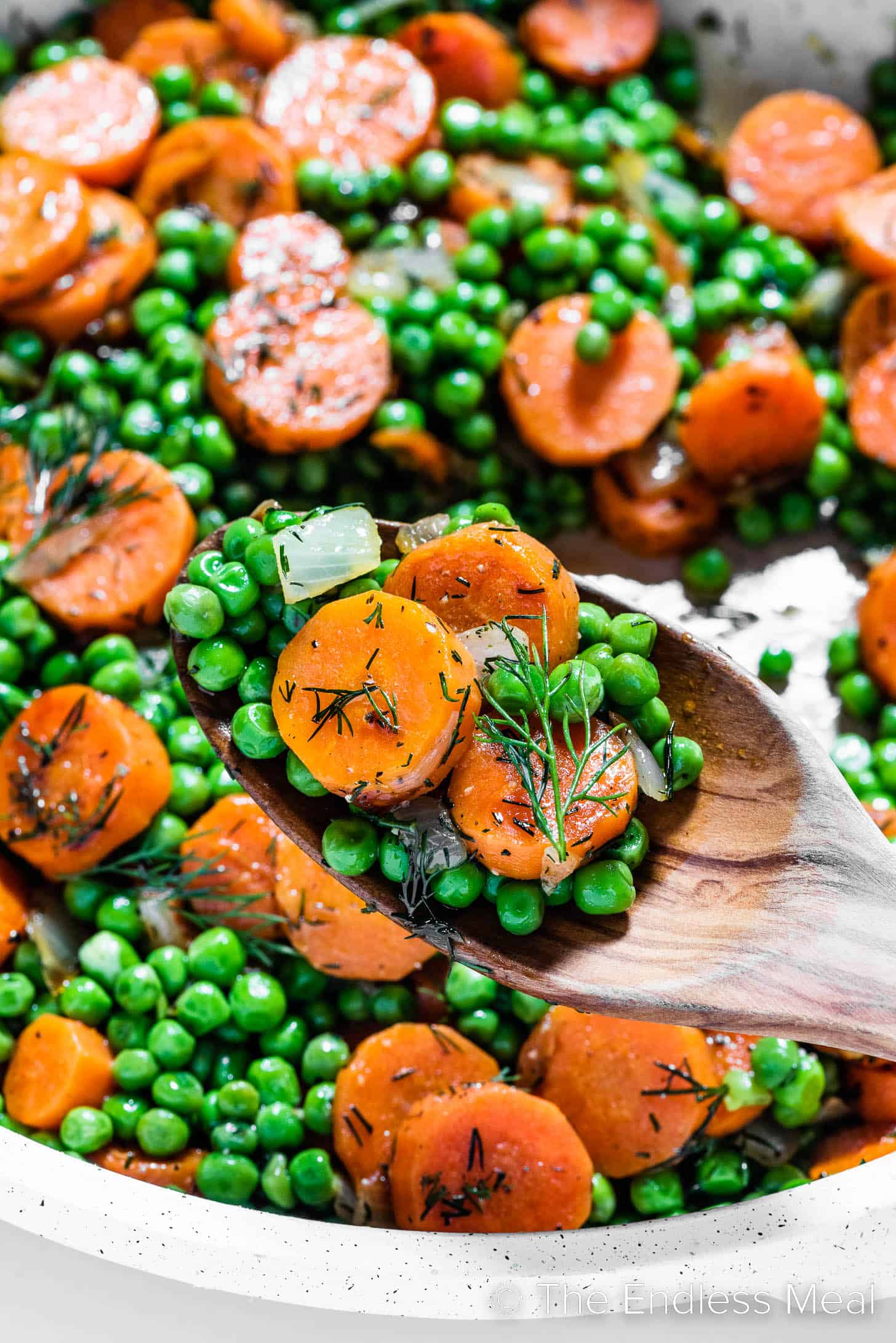 A close up of Peas and Carrots in a pan