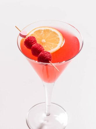 A Raspberry Martini with fresh raspberries and a lemon slice