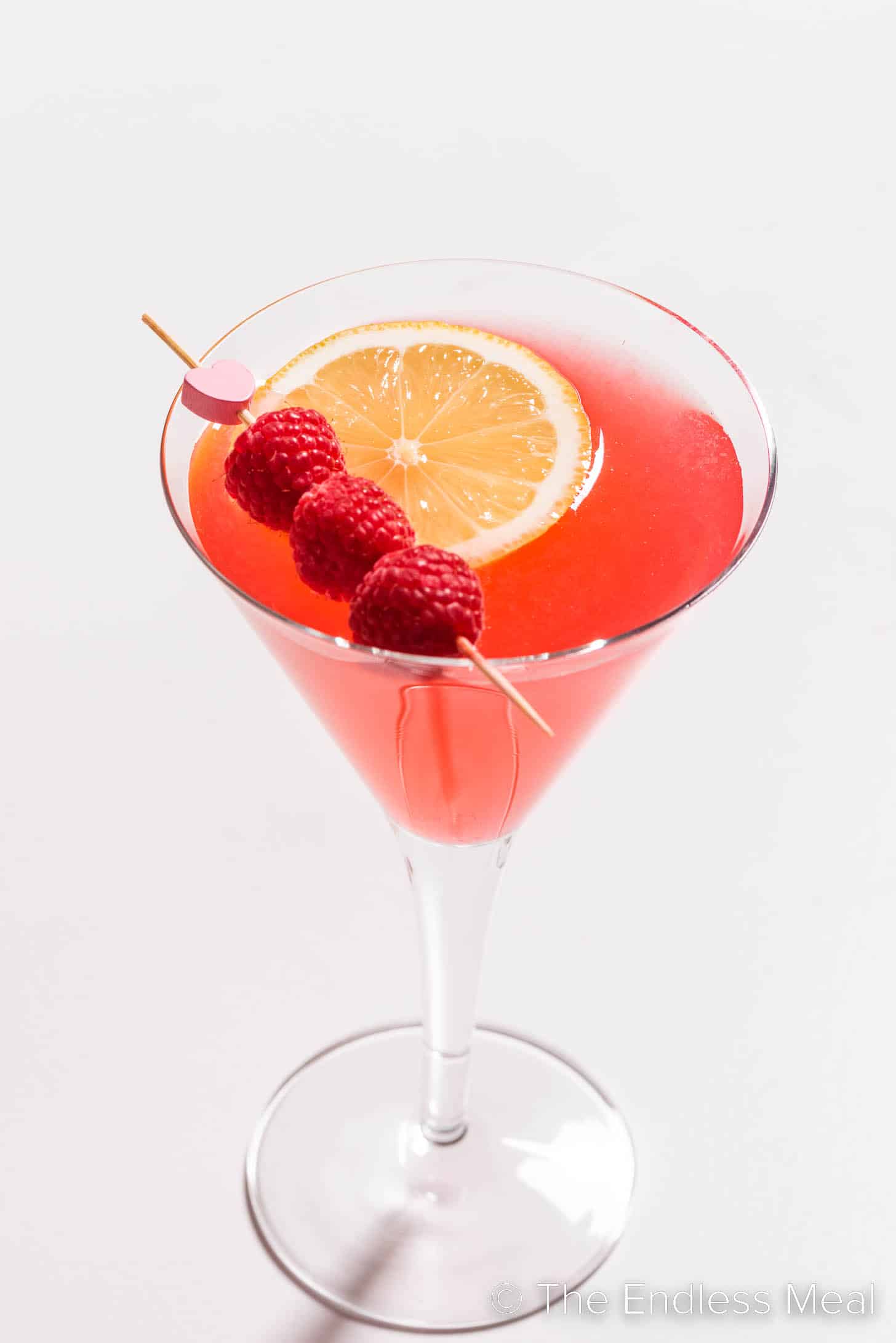 A Raspberry Martini with fresh raspberries and a lemon slice