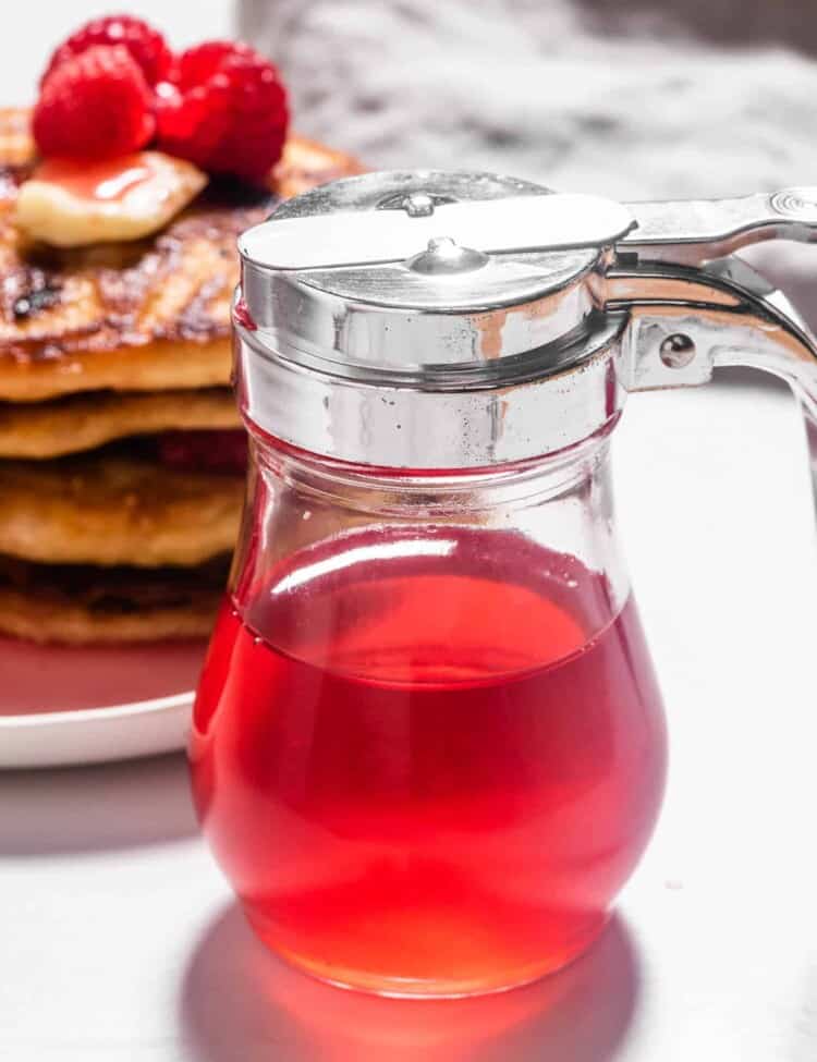Raspberry Simple Syrup next to a stack pf pancakes