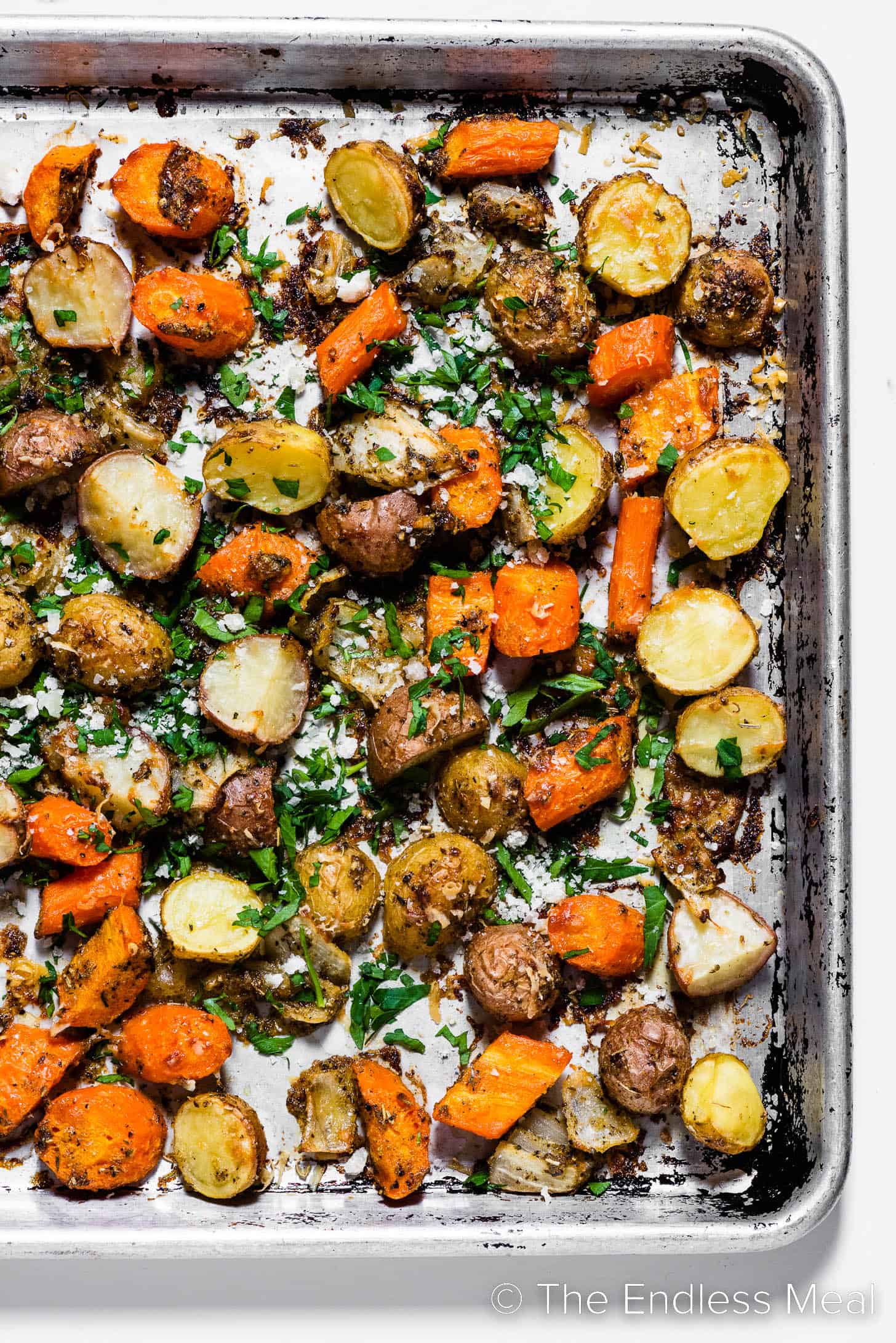 Roasted carrots, potatoes, and onions on a baking sheet