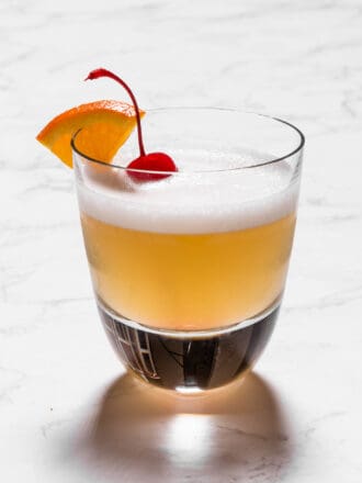 A bourbon sour in a rocks glass with a cocktail cherry