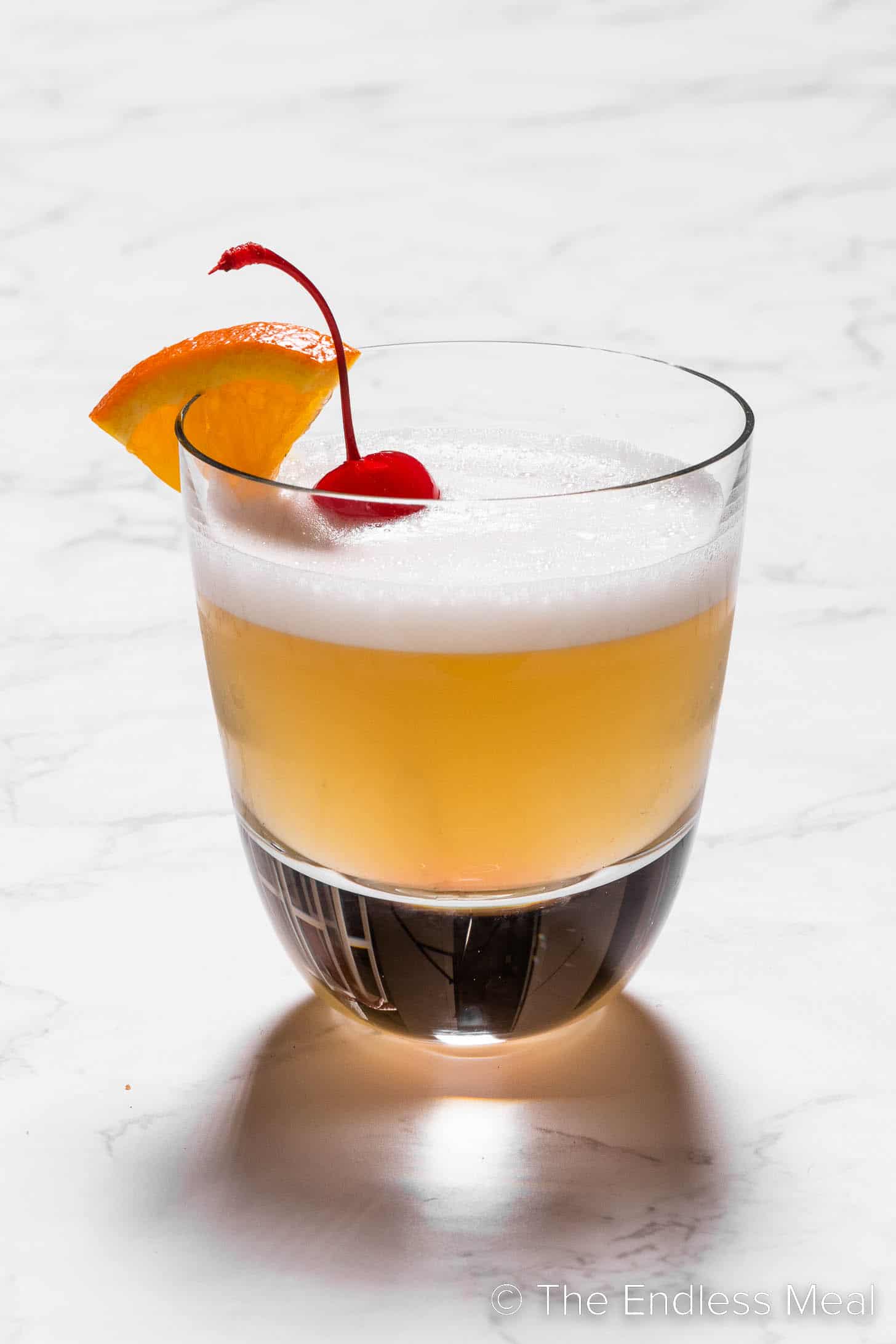 A bourbon sour in a rocks glass with a cocktail cherry