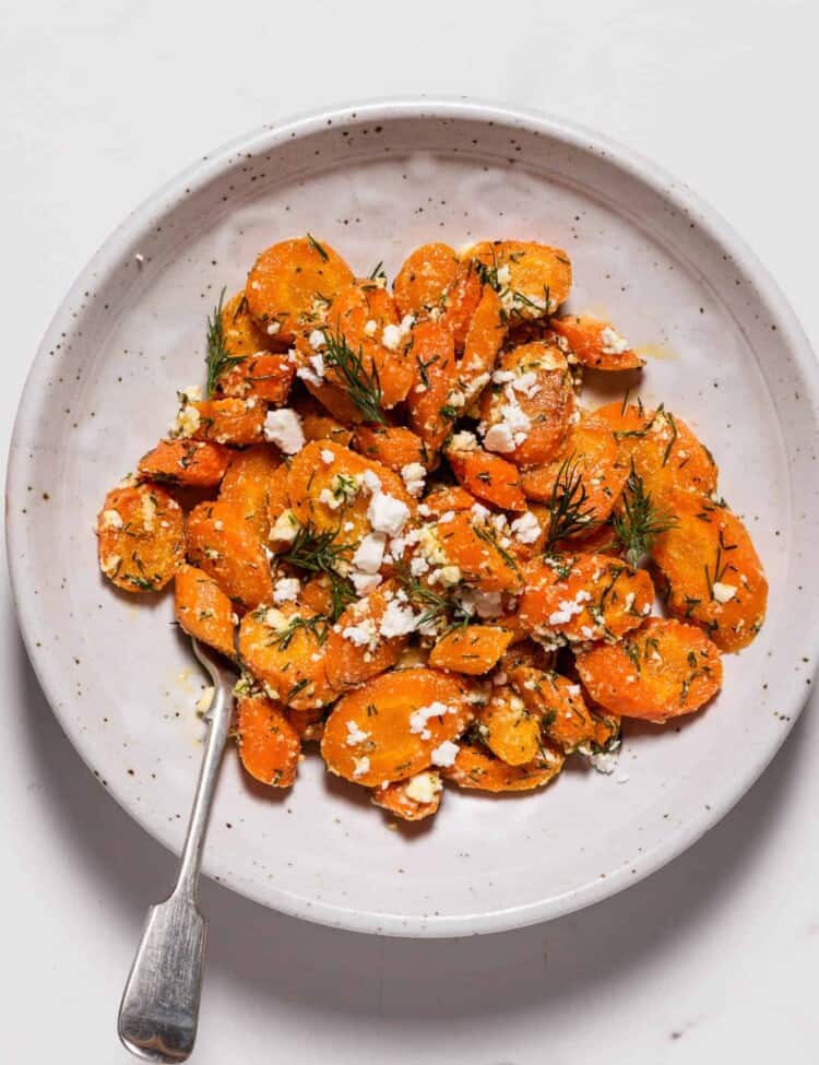 roasted carrots with dill on a plate with a spoon