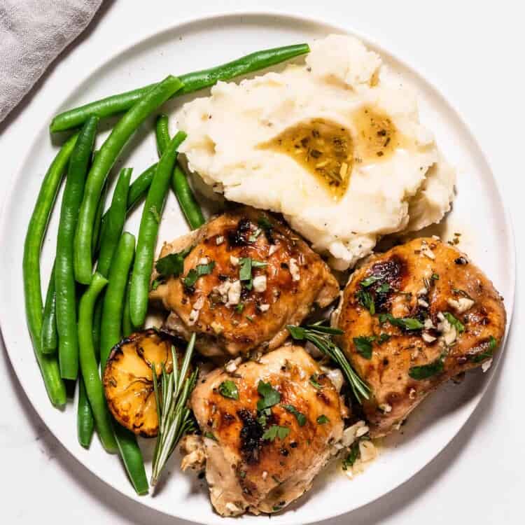 Lemon Rosemary Chicken Thighs on a plate with mashed potatoes and green beans.