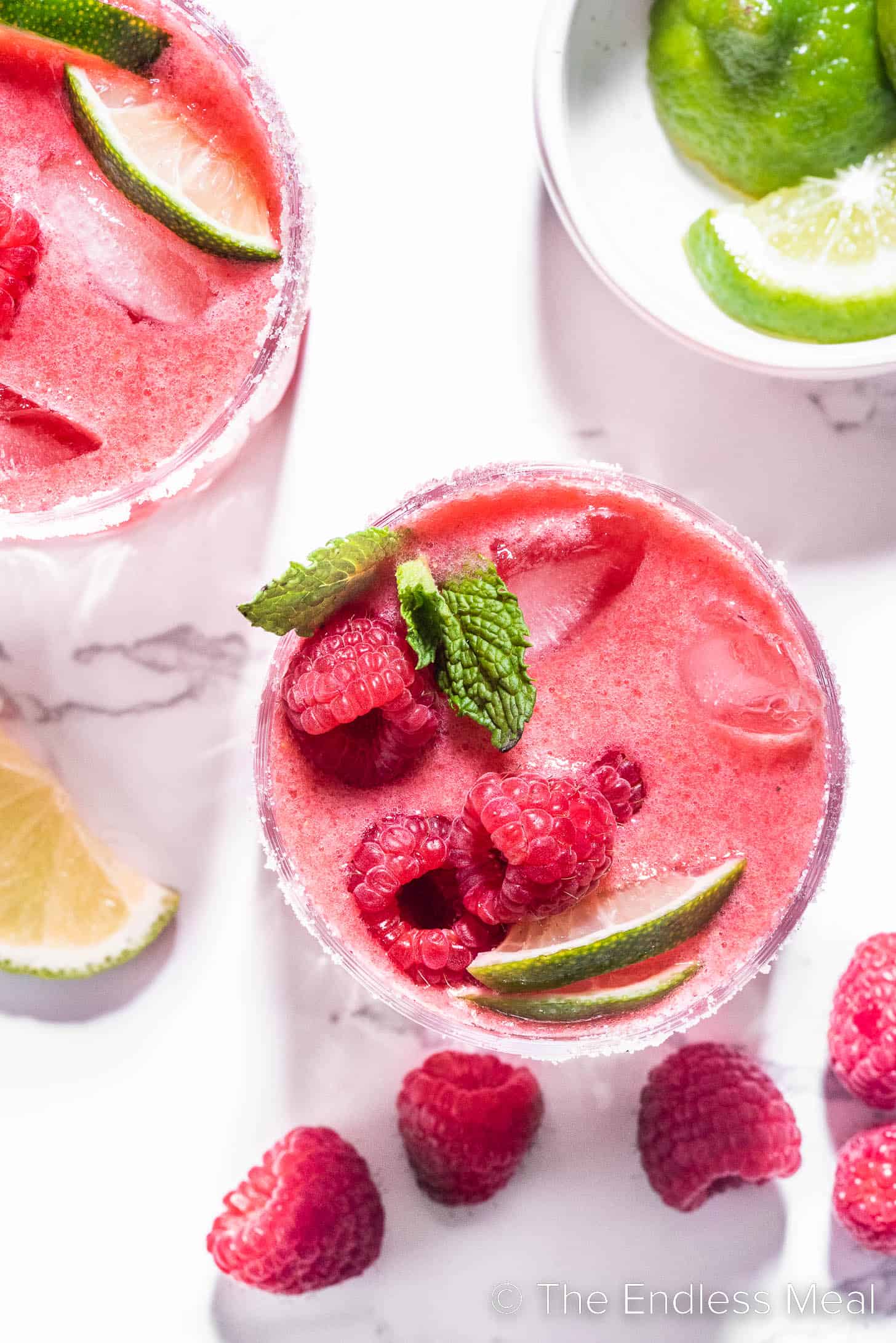 A fresh Raspberry Margarita in a glass with lime.