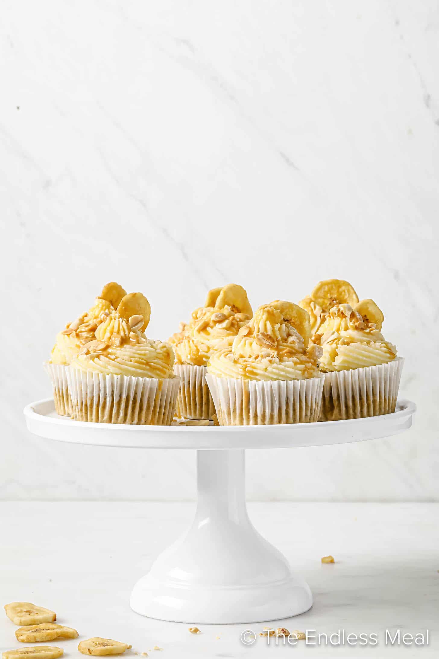 A cake stand with Peanut Butter Banana Cupcakes on top.