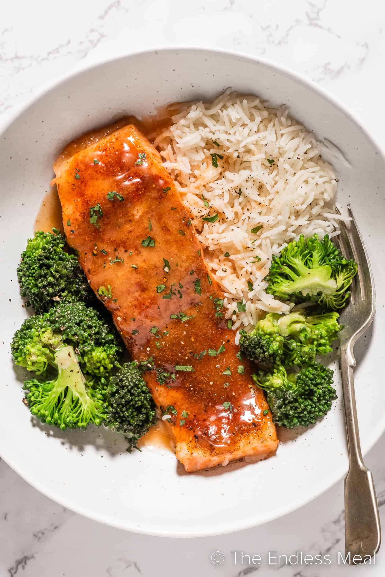 A piece of Bang Bang Salmon on a plate with rice and broccoli