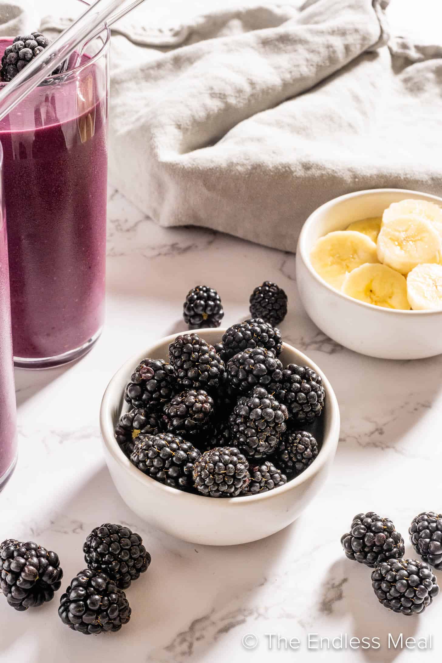 A bowl of blackberries next to a smoothie