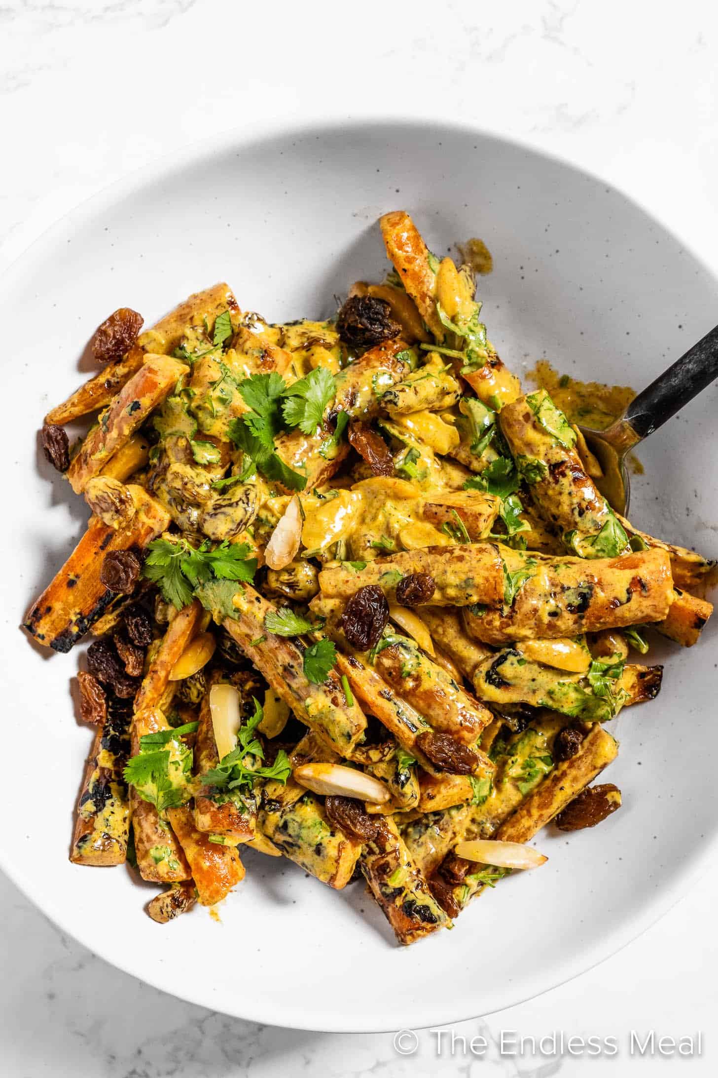 Grilled Curried Carrots in a bowl with a serving spoon