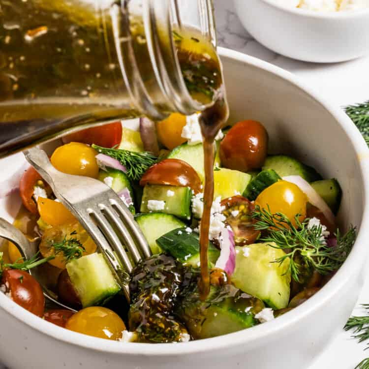 Pouring Greek Salad Dressing over a Greek salad