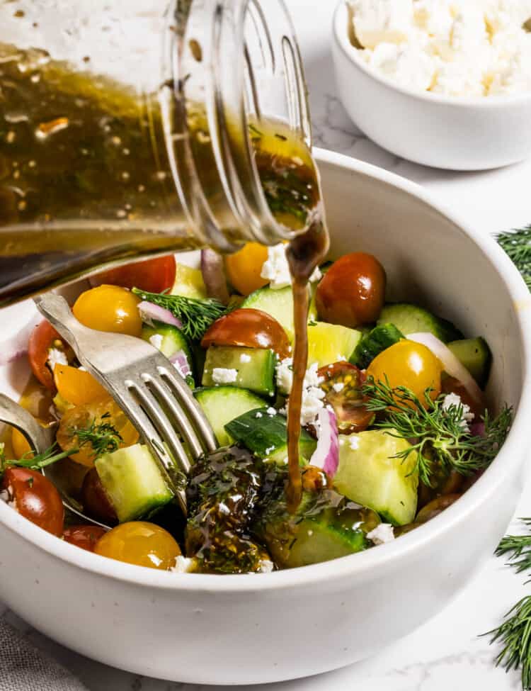 Pouring Greek Salad Dressing over a Greek salad